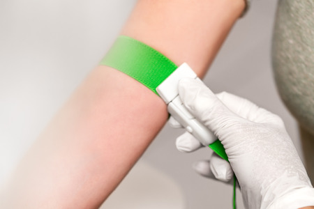 Patient with a tourniquet band on the arm, preparation for blood drawing, closeup