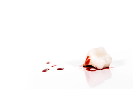 Concept image with bloody tooth in front of white background