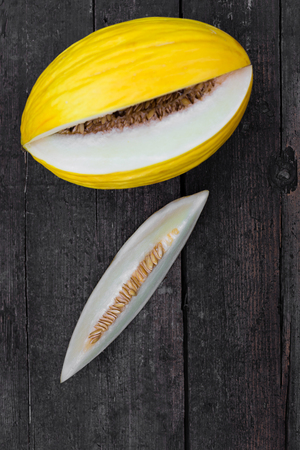 topview on a canary melon and slice on a wooden dark tableの写真素材