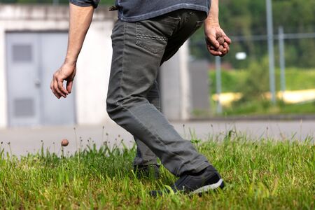 man is holding and throwing seed balls or seed bombs in front of a ugly grey building, concept...