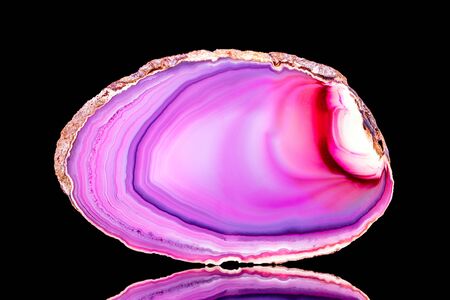 Pink agate slice mineral in front of black background, mineralogy and esotericism