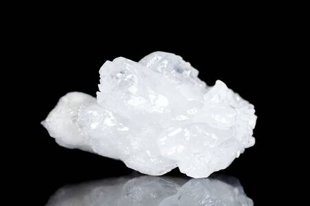 Raw white quartz mineral stone in front of black background, mineralogy and esotericism