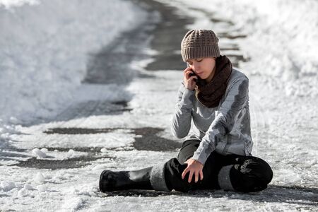 Woman slipped on winter road with black ice, emergency call for help, accident and injury, copyspaceの写真素材