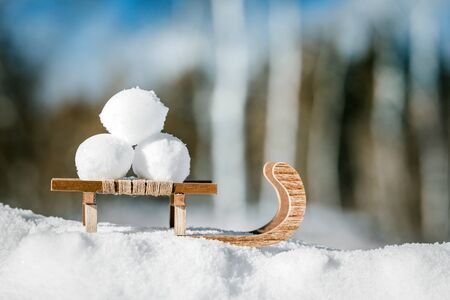 Little wooden sledge standing in the snow, three snowballs on it, concept vacation and fun at winter seasonの写真素材