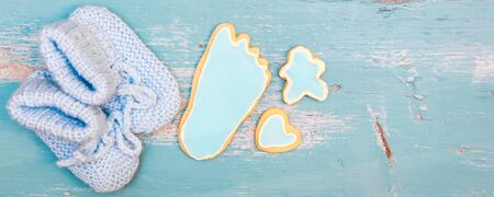 Header for Birth from a newborn boy, blue cookies and little shoes on blue table, copyspace
