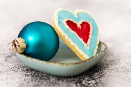 delicious heart shape cookie and blue christmas ball on a grey tableの写真素材