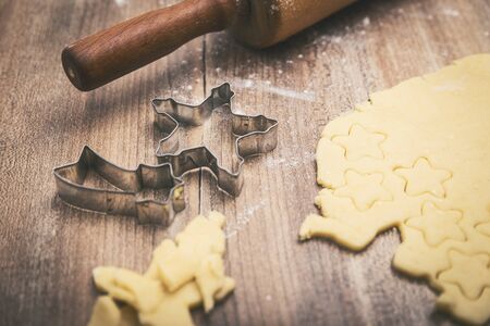 Christmas bakery background with raw cookie dough, cutters and wooden rolling pin の写真素材