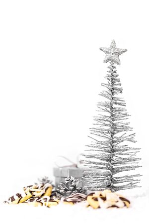 Metallic christmas tree, gift box and cookies on white snow, copyspaceの写真素材