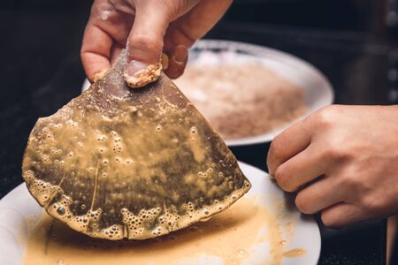 woman is preparation a big oyster mushrooms for a gourmet dining meal, egg and bread as coating