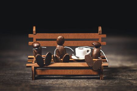Coffee bean figures having a break on a wooden bench