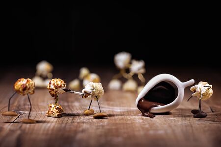funny popcorn figures are glacing or dipping others with chocolate, chocolate icing on party snacks の写真素材