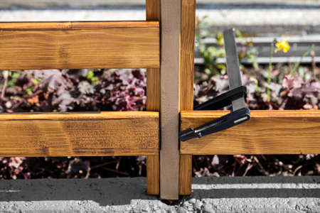 wooden board is attached to a railing with a screw clamp, prepared for screwing