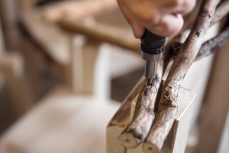 craftsman screws a branch as armrest to a rustic wooden chair