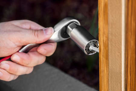 male hand is using a universal adjustable socket wrench to tighten a bolt