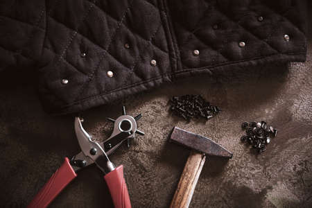 a lot of tools like a leather punch plier or a hammer and some copper rivets, crafting leathercraft equipment on a brown backgoundの写真素材