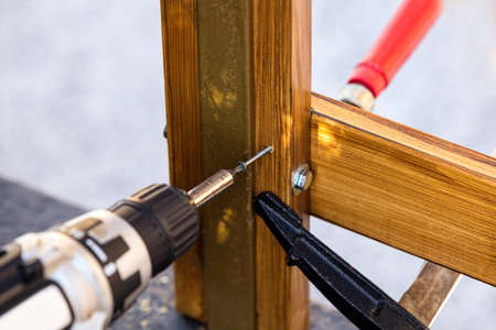 a screw is screwed into wood with a cordless screwdriver, board is fixed with screw clamps