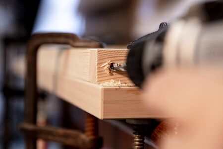 a hole is drilled in wood with a cordless screwdriver, fixing with screw clamps