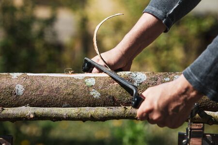a man is shaving an wooden log with an drawknife