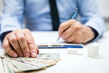 Businessman with us dollars and symbolic houses and building projects, bodypart handsの写真素材