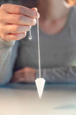 Fortuneteller is holding an crystal pendulum, spiritually librate and esoteric, closeup