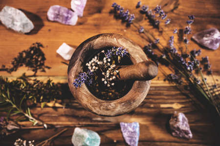Pulverizing healing herbs and flowers with the mortar, esoteric ingredients for a therapy, flatlay