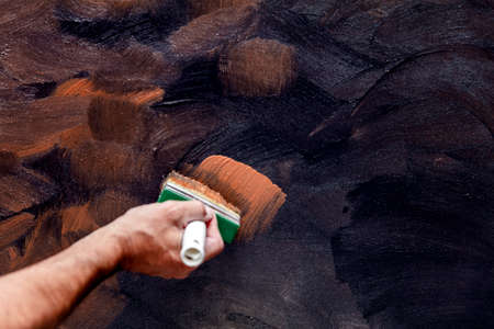 a wall is painted with a rust effect paint by a man
