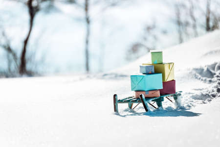 Colorful presents on a wooden sledge standing in the snow, concept christmas and winter season
