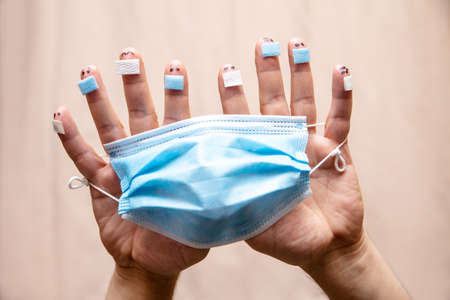 Two hands with finger figures wearing a surgical face mask, concept social distancing in days of corona pandemicの写真素材