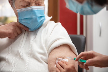 senior adult elderly woman with gray hair is receiving a vaccination against covid, concept pandemic protection or fluの写真素材