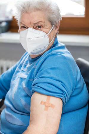 a senior woman has a patch on her upper arm after a vaccination