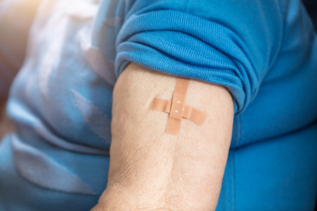 a senior woman has a patch on her upper arm after a vaccinationの写真素材