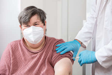 mentally disabled or handicapped woman is getting a vaccination from a male doctor or nurseの写真素材