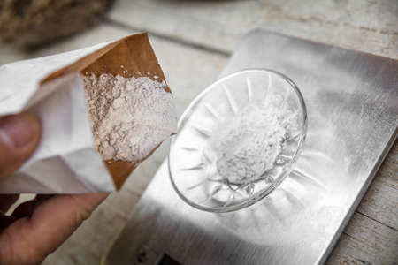 a bowl on a scale is getting filled with gypsum out of a bag