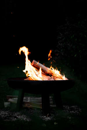 Campfire on a fire bowl, dark night background, barbecue camping, copyspaceの写真素材