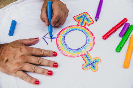 man with painted fingernails paints the lgbt symbol on a shirt. concept lgbt and diversityの写真素材