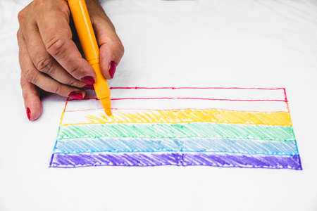 man with painted fingernails paints the rainbow flag on a shirt. concept lgbt and diversityの写真素材