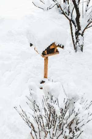 Wooden Bird feeder standing in the snow, feeding birdseed at winter time, copyspaceの写真素材