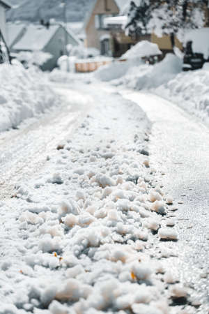 Snow and black ice at the street, village covered with snow at winter seasonの写真素材