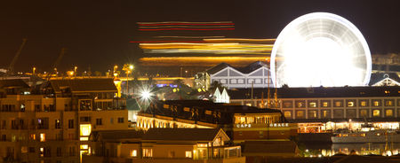 Panoramic night shoth towards cape town harbour waterfront showing ship and big wheel movementの写真素材