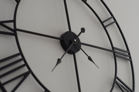 close up office wall white clock with black arrows.