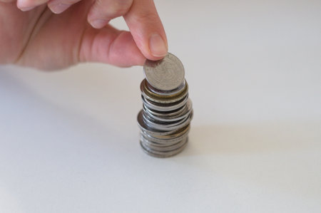 close up hand stacking coins on white background.