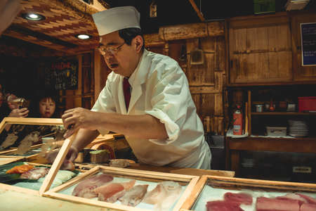 Sushi master chef preparing fresh sashimi for hungry customers in a luxury sushi restaurant in Tokyo Japanのeditorial素材