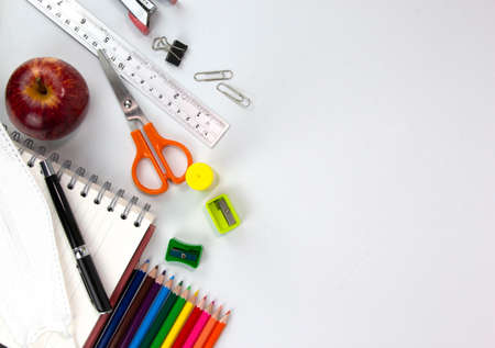Education elements concepts, color pencils, face mask, paper clips, scissors, ruler, apple isolated on white background. Back to school conceptの写真素材