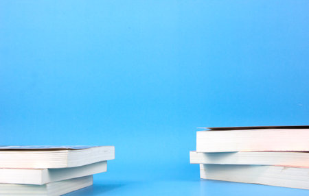 Books place on two side of blue background. Composition with different school stationery light blue...