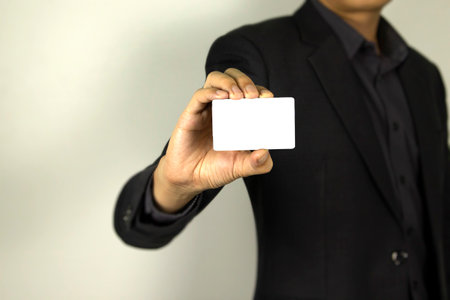 Business Man wearing smart suit and holding whit ID card in his hand, A smart man holding white mock up card, used in card design poster.の写真素材