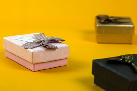 wonderful golden gift box with ribbons background on yellow BG, A focus golden box, set of Gift boxes on yellow background.の写真素材