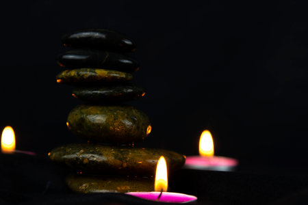 Layers of stones are on dark background, two rounded candlesの写真素材