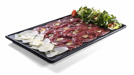 Veal meat carpaccio with slices of parmesan and vegetable salad mix on black square plate garnished with fried white mushrooms isolated on white backgroundの写真素材