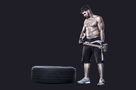 Athlete with a sledgehammer prepairing to hit  tire isolated on black backgroundの写真素材