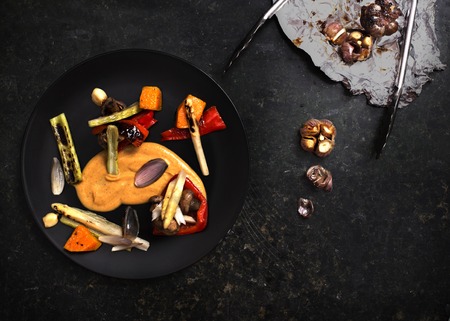 Colourful grilled vegetables seasoned with mustard in black plate on granitic backgroundの写真素材
